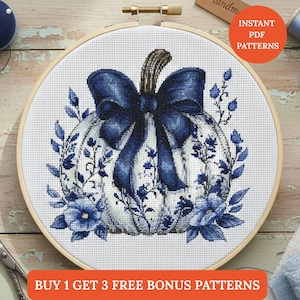 Peut inclure: Motif de point de croix d'une citrouille avec un grand nœud bleu et des motifs floraux, dans un cercle à broder en bois. La citrouille est blanche avec des détails bleus. Le texte indique "Instant PDF Patterns" et "Buy 1 Get 3 Free Bonus Patterns".