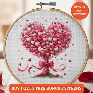 Op de afbeelding: Kruissteekborduurwerk in een houten hoepel toont een hartvormige boom bestaande uit rode en roze harten. Een rode strik siert de basis, met linten die naar beneden stromen. De tekst "INSTANT PDF PATTERNS" en "BUY 1 GET 3 FREE BONUS PATTERNS" zijn zichtbaar.