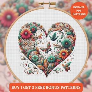 Op de afbeelding: Een kruissteekpatroon in een houten borduurring, met een hartontwerp gevuld met kleurrijke bloemen, vlinders en wervelende ranken. De tekst "INSTANT PDF PATTERNS" en "BUY 1 GET 3 FREE BONUS PATTERNS" zijn ook zichtbaar.