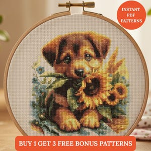 May include: Cross-stitch embroidery of a brown puppy holding a sunflower in its mouth, surrounded by blue flowers. The artwork is displayed in a wooden embroidery hoop. Text on the image reads "Instant PDF Patterns" and "Buy 1 Get 3 Free Bonus Patterns."