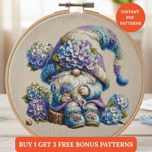 May include: A cross-stitch pattern of a gnome in a blue and purple outfit, surrounded by blue and purple hydrangeas, displayed in a wooden embroidery hoop. The image includes the text "INSTANT PDF PATTERNS" and "BUY 1 GET 3 FREE BONUS PATTERNS."