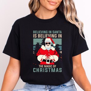 Christmas T-Shirt Believing in Santa Women Shirts Merry Christmas Gift for Her Merry Christmas Shirt Gift for Mom Christmas Tee Gift for Him