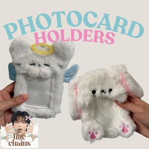 May include: Two plush photo card holders. One is a white angel with blue wings and a halo. The other is a white bunny with pink ears and paws. Both have a slot for a photo card.