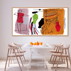 K&ouml;nnte beinhalten: Abstrakter Kunstdruck mit einem Mann, der einen Hut und eine Brille tr&auml;gt, in einem roten, orangefarbenen, gr&uuml;nen und blauen Farbschema. Der Druck ist gerahmt und h&auml;ngt an einer wei&szlig;en Wand &uuml;ber einem wei&szlig;en Tisch mit vier Holzst&uuml;hlen.