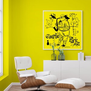 May include: A black and white illustration of a bird playing a saxophone with the text "Charlie Parker" on a yellow background. The illustration is framed and hanging on a yellow wall.