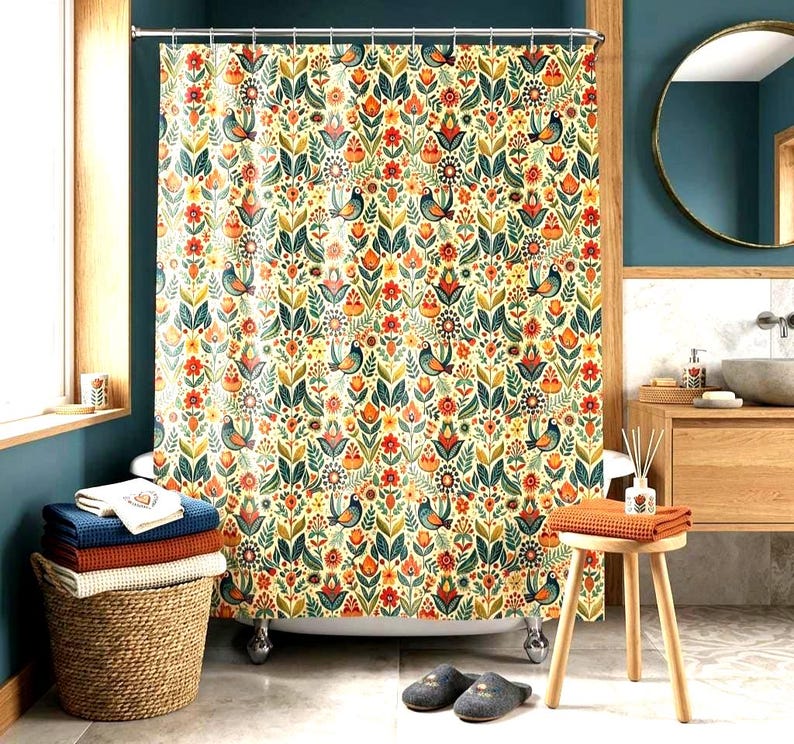 May include: A floral shower curtain with a cream background, featuring a repeating pattern of birds, flowers, and leaves in orange, green, and blue. The curtain hangs in front of a white bathtub with silver feet. A wicker basket holds folded towels.