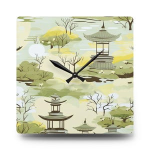 May include: Square wall clock with a Japanese garden design. The clock face features a serene landscape with pagodas, trees, and a soft color palette of greens, yellows, and browns. Black clock hands indicate the time.