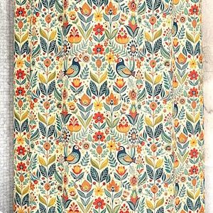 May include: A shower curtain with a repeating pattern of stylized birds, flowers, and leaves in shades of orange, yellow, teal, and green on a cream background. The design has a folk art style, creating a vibrant and decorative bathroom accessory.