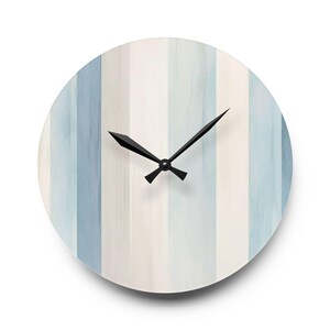 Könnte beinhalten: Runde Wanduhr mit vertikal gestreiftem Design in Blau- und Weißtönen. Die Uhr hat schwarze Zeiger und ein minimalistisches Design, ideal für die Inneneinrichtung. Der Durchmesser der Uhr beträgt ca. 30 cm.
