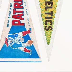 Puede incluir: Banderines triangulares con logotipos y texto de equipos. Un bander&iacute;n presenta el logotipo de los New England Patriots con el texto "PATRIOTS" en rojo y azul. Otro bander&iacute;n muestra el logotipo de los Boston Celtics con el texto "CELTICS" en verde y amarillo.