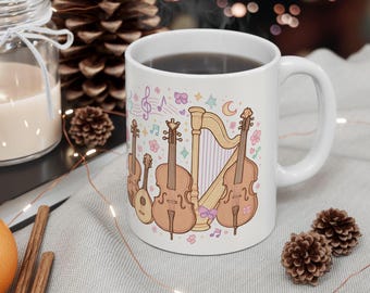 May include: White ceramic mug featuring a whimsical illustration of stringed instruments, including a violin, cello, and harp, with musical notes and floral accents. The mug has a curved handle and is filled with a dark liquid.