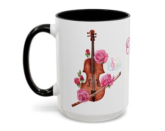May include: White ceramic mug with a black handle and rim. The mug features a watercolor illustration of a violin, pink roses, musical notes, and a bow. The word "Grace" is written in pink script.
