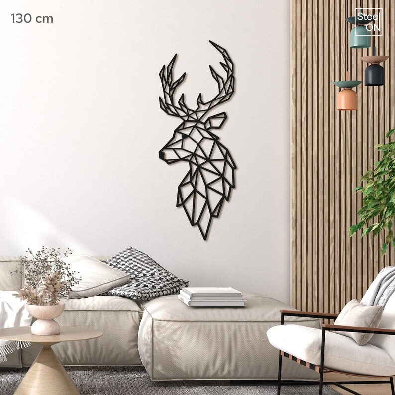 May include: Black geometric deer head wall decor, 130 cm in size, displayed on a white wall in a living room setting with a couch and chair.