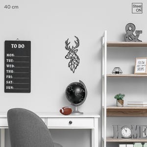 May include: Black and white geometric deer head wall decor, 40 cm in size, with a black globe, a football, a to-do list, and a shelf with home decor items, including a sign that says "Follow your dreams".