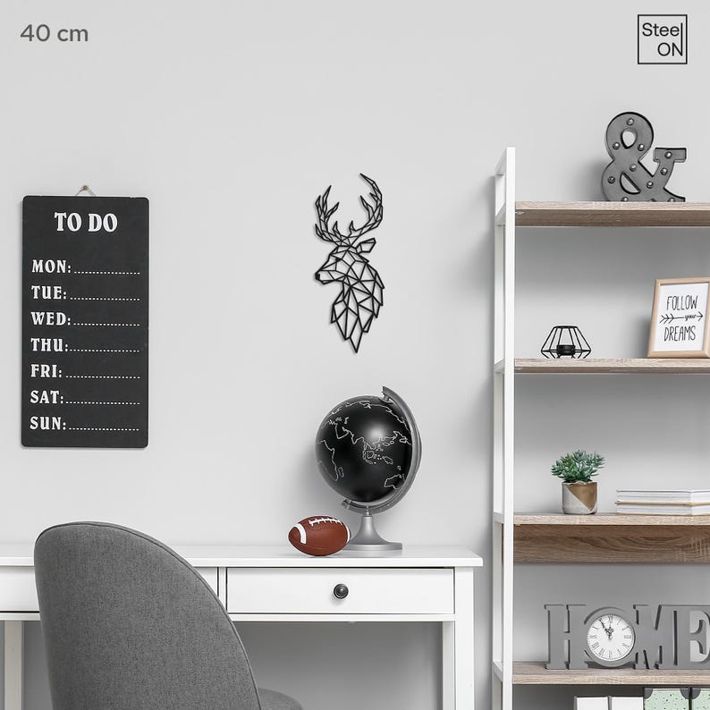 May include: Black and white geometric deer head wall decor, 40 cm in size, with a black globe, a football, a to-do list, and a shelf with home decor items, including a sign that says "Follow your dreams".