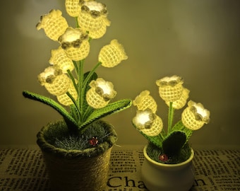 May include: Two decorative flower arrangements with glowing yellow crochet flowers. One is in a woven pot, the other in a white ceramic pot. Both have green leaves and a small ladybug.