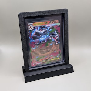 May include: A black display stand holding a Pokemon trading card. The card features a Mega Charizard EX with a fiery design and the text "Inferno X". The stand is made of black plastic.