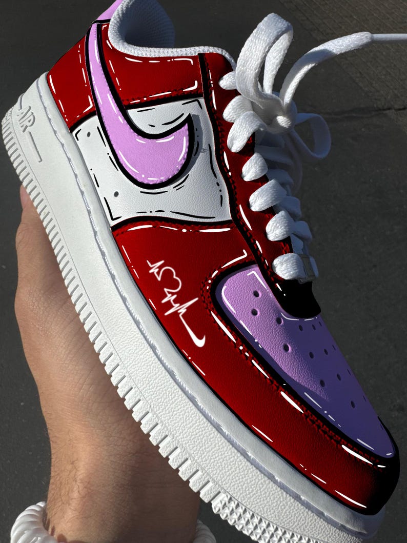 May include: Customized red, white, and pink Air Force 1 sneakers. The shoe features a heart and heartbeat design on the side, with a pink Nike swoosh. White laces and a white sole complete the design.