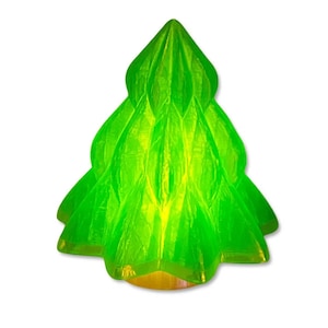 Puede incluir: Un adorno de árbol de Navidad verde translúcido y vibrante. El árbol tiene un diseño en capas con una parte superior puntiaguda y una base amarilla. El adorno está hecho de un material brillante y está sobre un fondo blanco.