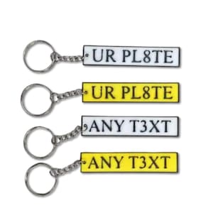 May include: Four keyrings with rectangular tags. Two tags are white with the text "UR PL8TE" and two are yellow with the text "ANY T3XT". Each keyring has a silver chain and a silver key ring.