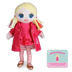 May include: A plush doll with blonde hair, blue eyes, and a pink dress. The doll is wearing a pink coat with a pocket that has a compass and ruler design. The doll is holding a book that says "STEAM Kids Engineering Activity Book". The book has a picture of a girl with blonde hair wearing a pink dress and holding a book. The text on the book says "Elaine aspires to become a confident engineer. Assist Elaine with her engineering skills."