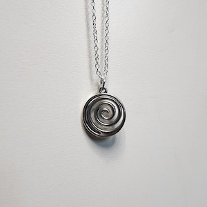 May include: A silver necklace with a spiral pendant. The pendant is round and has a silver chain.