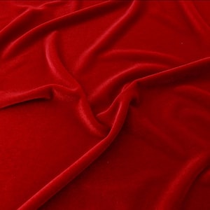 May include: A close-up of a smooth, red velvet fabric with soft folds and wrinkles.
