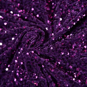 May include: Purple velvet fabric with sequins. The fabric is tightly woven and has a soft, luxurious feel.