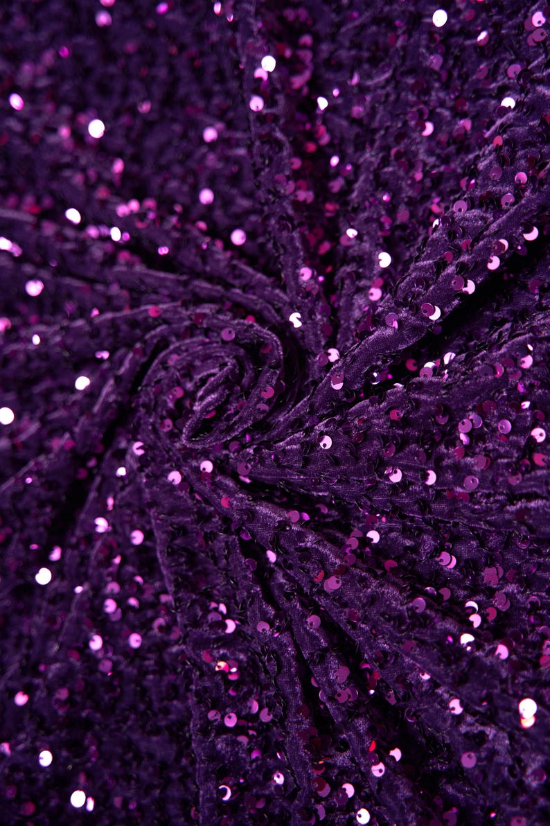 May include: Purple velvet fabric with sequins. The fabric is tightly woven and has a soft, luxurious feel.