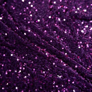 May include: Purple fabric with a textured surface covered in small, iridescent sequins.
