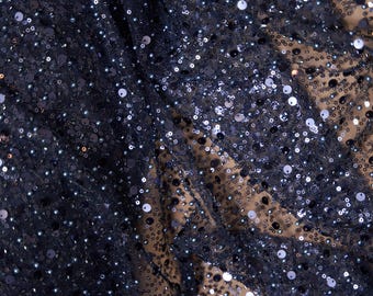May include: Navy blue fabric with a sparkly, iridescent finish. The fabric is covered in small, round sequins.