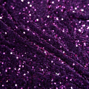 May include: Purple fabric with a textured surface covered in small, round sequins.