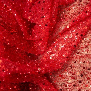 May include: Red fabric with small, round sequins. The sequins are scattered randomly across the fabric, creating a sparkly effect.