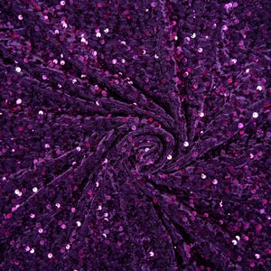 May include: Purple velvet fabric with sequins. The fabric is gathered in a swirl pattern.