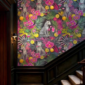 May include: A colourful wallpaper design showcasing a jungle scene with leopards, cocktails, and tropical flowers. The pattern includes pink orchids, yellow citrus fruits, and green leaves set against a dark backdrop. The wallpaper is displayed on a wall in a home's hallway.
