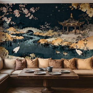 Könnte beinhalten: Ein detailliertes Wandbild, das eine asiatische Landschaft mit einer Pagode, einer Brücke und Wasserelementen darstellt. Die Szene umfasst Kraniche, Enten und Kirschblüten. Das Wandbild befindet sich über einem eingebauten Sitzbereich mit einem Holztisch und dekorativen Kissen.