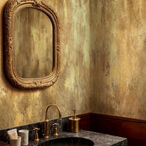 Elegant bathroom vanity featuring a black marble sink and ornate gold mirror. Faux Gold Wall Covering mimicking antique plaster and a wabi sabi metallic effect for a luxury powder room.
