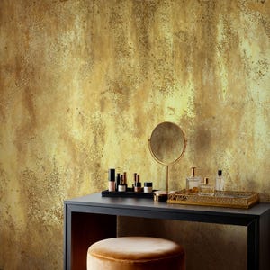 Chic makeup vanity table with cosmetics, a round mirror, and a velvet stool. Distressed Gold Effect Wall Mural creating a stylish wabi sabi and vintage glam backdrop for a modern dressing room.