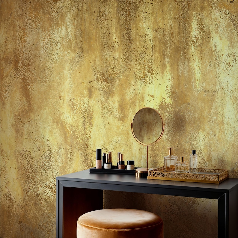 Chic makeup vanity table with cosmetics, a round mirror, and a velvet stool. Distressed Gold Effect Wall Mural creating a stylish wabi sabi and vintage glam backdrop for a modern dressing room.