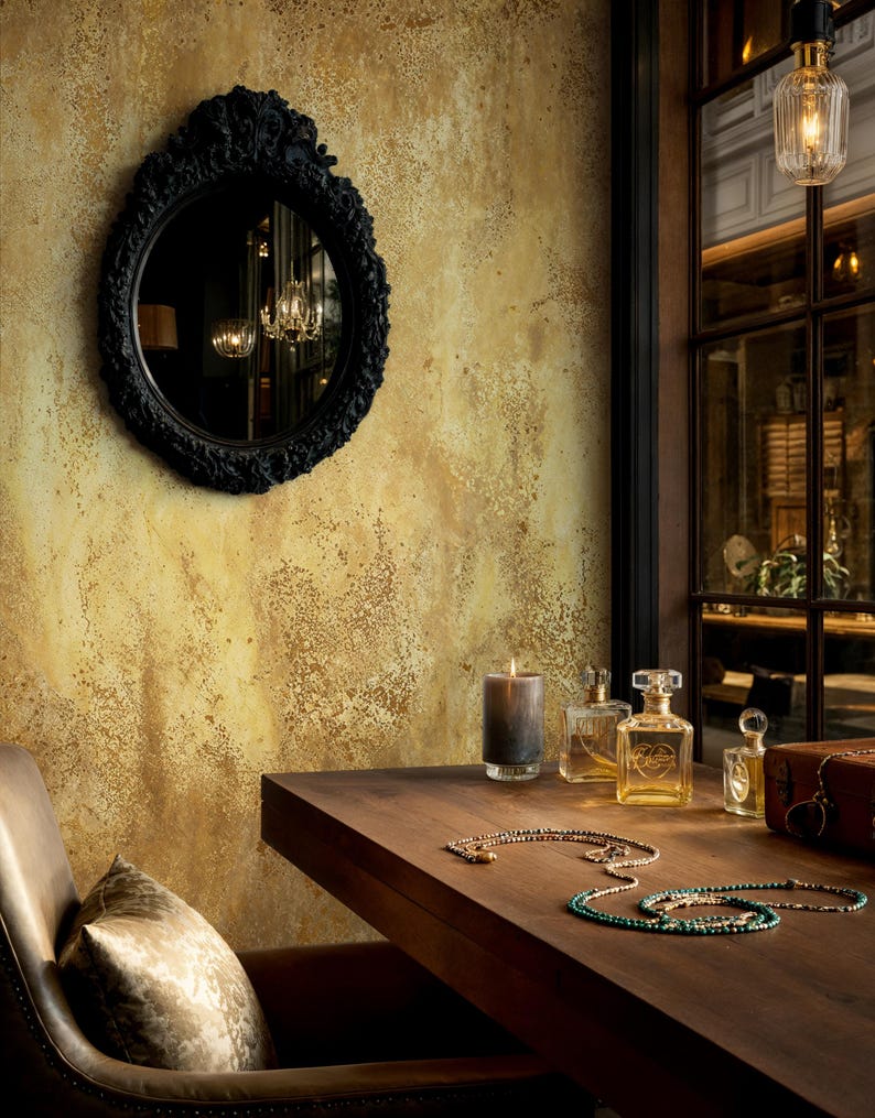 Moody vintage interior styling with an ornate black mirror and glass perfume bottles. Vintage Art Deco Wallpaper showing a printed grunge gold texture for a dramatic home office or vanity.