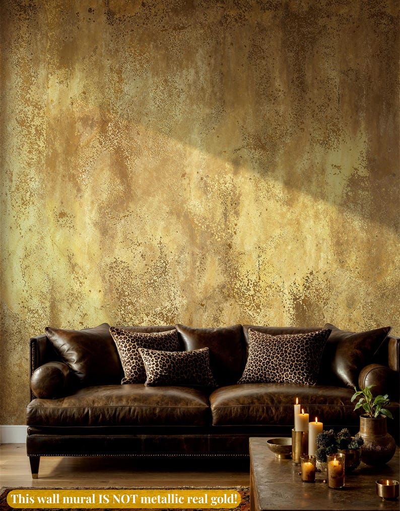 Masculine living room styling with a brown leather chesterfield sofa and leopard print pillows. Faux Gold Texture Peel and Stick Wallpaper displaying a printed grunge plaster effect without real metallic shine.