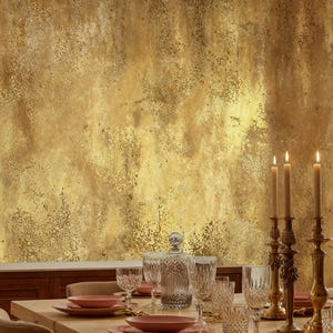 Sophisticated dining room table setting with crystal glassware and classic brass candlesticks. Rustic Grunge Wall Mural in faux gold adding a warm, textured plaster illusion to the dining area.