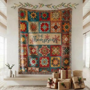 Puede incluir: Una manta tejida con un colorido mosaico de patrones cuadrados inspirados en flores en rojo, azul, amarillo y verde. Un panel rectangular central muestra el texto "THE Thompsons" rodeado de ilustraciones de copos de nieve rojos.