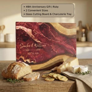 May include: A rectangular glass cutting board and charcuterie tray featuring a deep red and gold marbled pattern. The surface is personalized with the text Sandra & William and 40 Years. The board is displayed with bread and cheese.