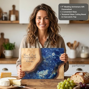 May include: A rectangular tempered glass cutting board and charcuterie tray featuring a natural wood grain edge and a deep blue marbled centre. The board is engraved with the text Olivia & David MASTERSON and 9 YEARS. It is a 9th wedding anniversary gift.
