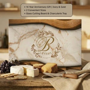 May include: A rectangular glass cutting board and charcuterie tray featuring an ivory and gold marble pattern with dark wood-toned edges. The center displays a gold letter B inside a leafy wreath with the text 14 Years below the letter.