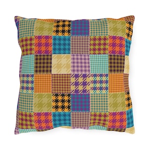 Puede incluir: Una almohada de patchwork colorida con un patrón de pata de gallo en tonos naranja, amarillo, morado, azul y negro.