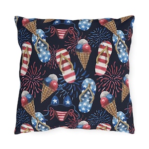 Puede incluir: Una almohada azul marino con un patrón repetido de chanclas, conos de helado y fuegos artificiales rojo, blanco y azul.
