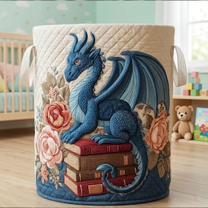 Puede incluir: Un cesto de almacenamiento acolchado con un diseño de dragón azul. El dragón está posado sobre una pila de libros, rodeado de detalles florales. El cesto tiene tela color crema con un patrón de diamantes, ribete azul y asas blancas.
