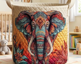 May include: A beige quilted storage basket with a colorful, detailed elephant design. The elephant features intricate patterns in shades of blue, red, orange, and yellow. The basket has two beige handles.